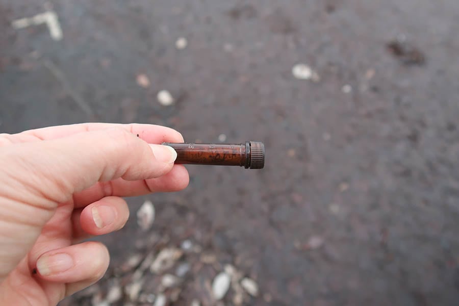 hand holding a brown tube with cap with a paper log inside