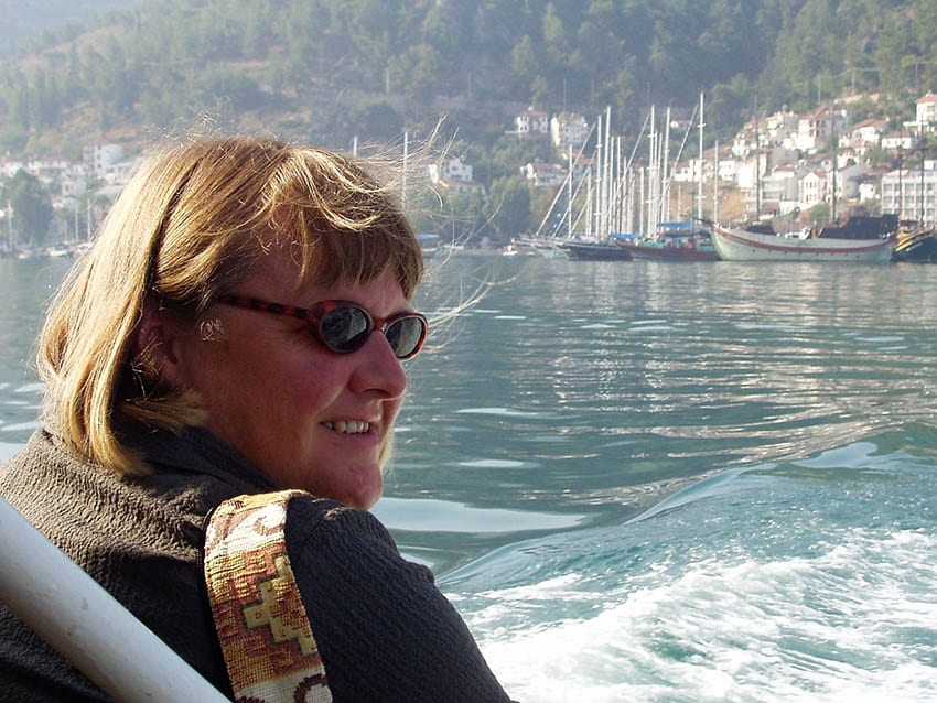 Andrea from Happy Days Travel Blog in Turkey wearing sunglasses with water and yachts in the background