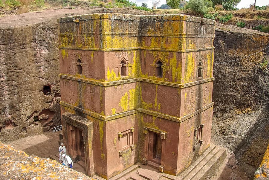 four storey church carved out of red rock with yellow discolouring on the walls and surrounded by the walls of the mine