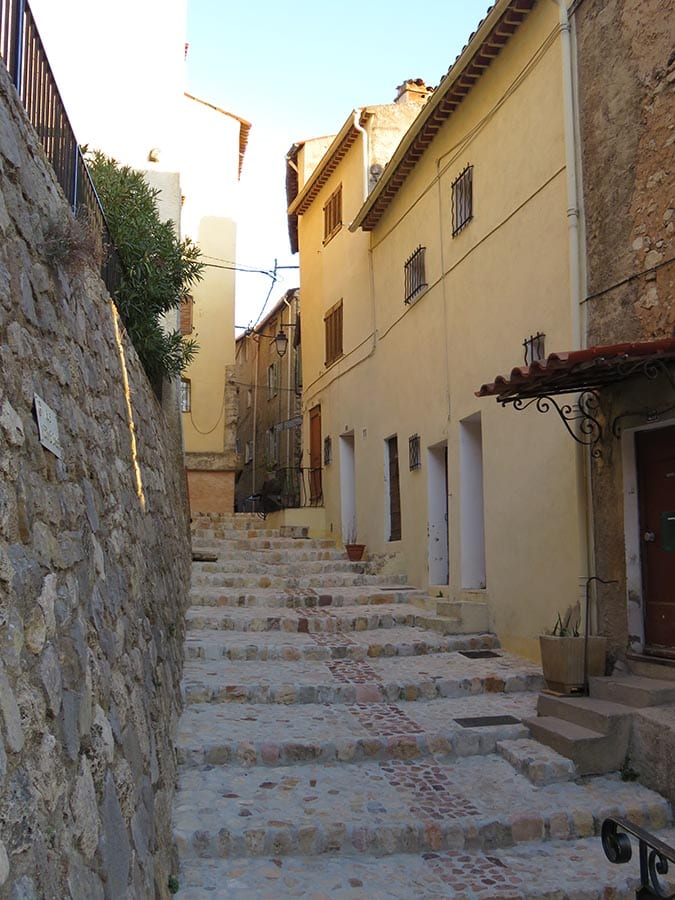 steps up between a wall on the left and a yellow building on the right in Callas