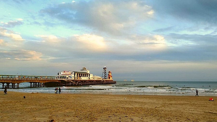 Bournemouth Pier with a helter skelter at the end with waves coming in over the sand