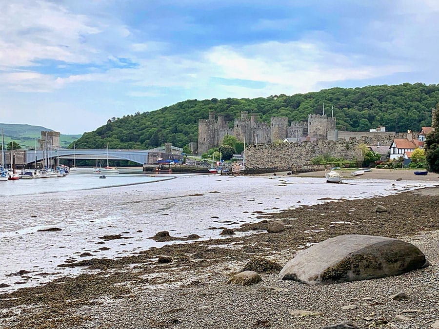 pebble beach with Castle Conwy in the background with a bridge over the river