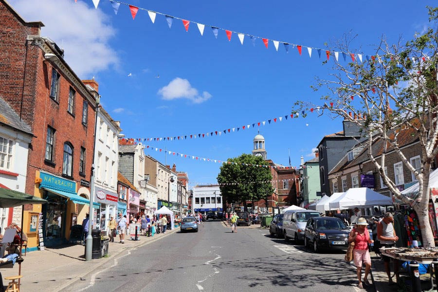 Bridport High Street with red, white and blue bunting and market stalls on the right