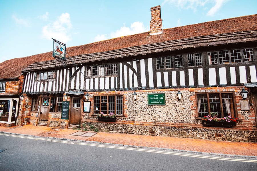 The George Inn, an oak beamed house with white render and black beams above stone walls