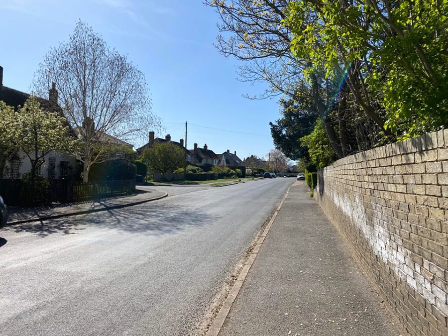 road with wall on the right and houses on the left