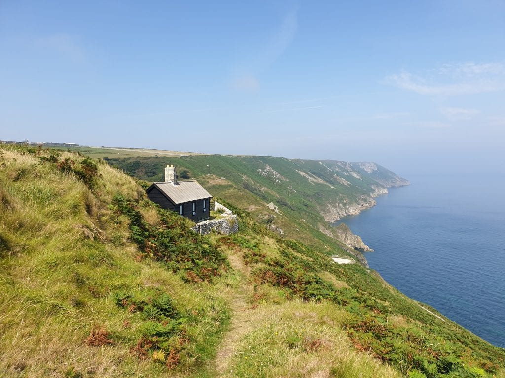 black wooden house sitting on the cliffside over looking the sea on Lundy Island