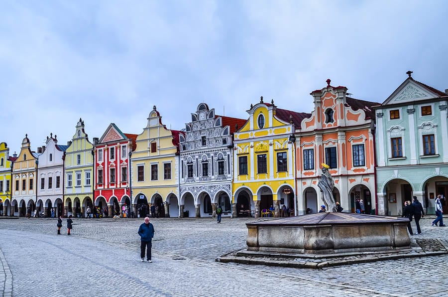 street in Telč of colourful houses in yellow, orange, pink red, grey and green. Each house front has a different shaped facades.