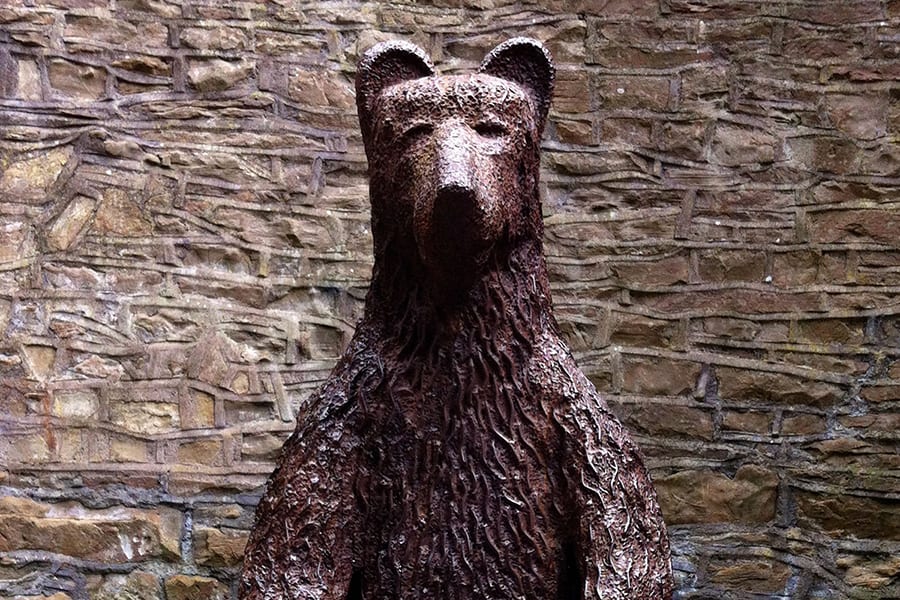 Statue of a bear with a stone wall behind