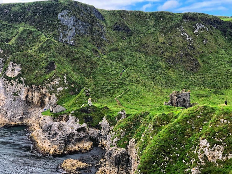 green hill leading down to the ruin of Kinbane Castle above the cliffs and rocks below