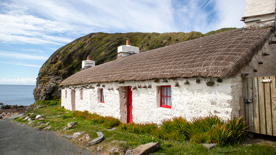 white Manx house with red door and window frames
