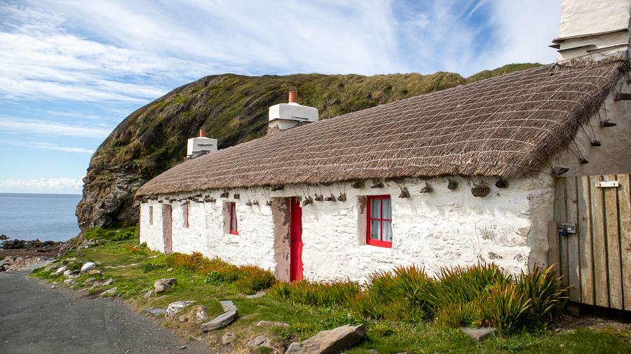 white Manx house with red door and window frames