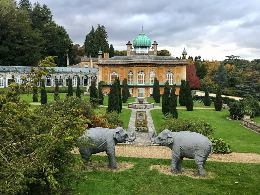 honey coloured building with copper onion dome with parkland in front of it and two elephant sculptures in the foreground