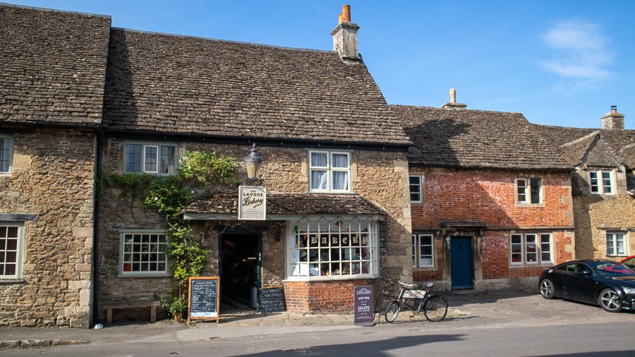 The beautiul Lacock Bakery in Church Street with honey coloured stonework, bay window and old black bicycle out front