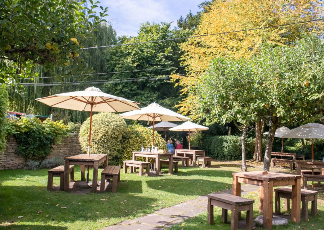 garden at Sign of the Angel with apple trees, tables, benches and umbrellas