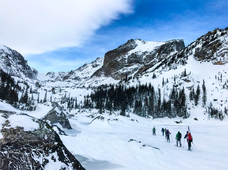 Rocky Mountain with skiers walking in the snow