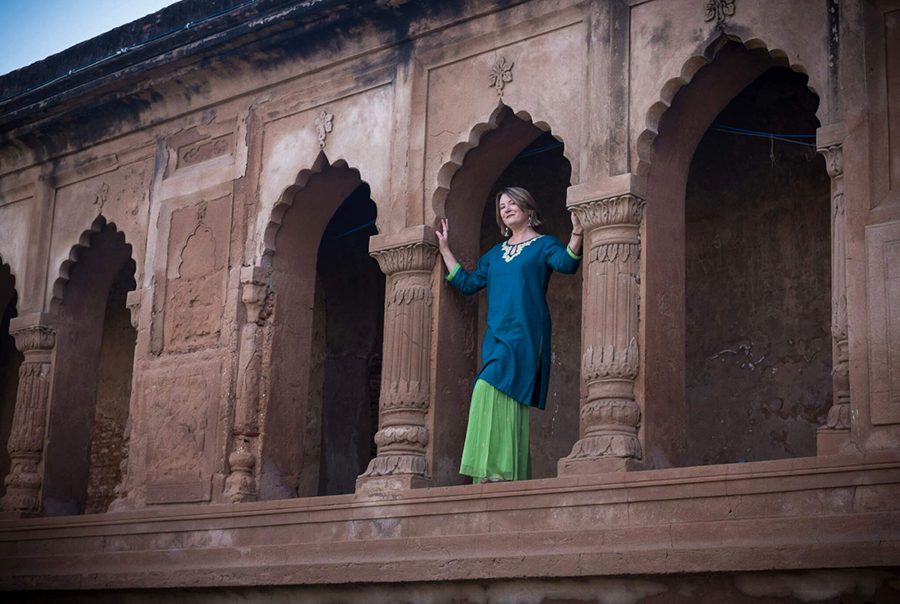 Mariellen from BreatheDreamGo in Lucknow wearing a blue tunic over a long green skirt and standing between ornate arches