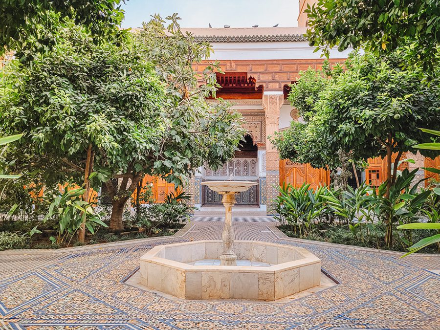 fountain with surrounded by blue and yellow tiles with ornate building behind