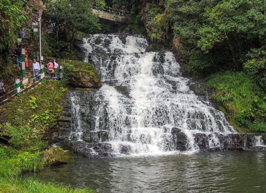 Multi-tiered waterfall with pool at the bottom. People walking down the steps to the left
