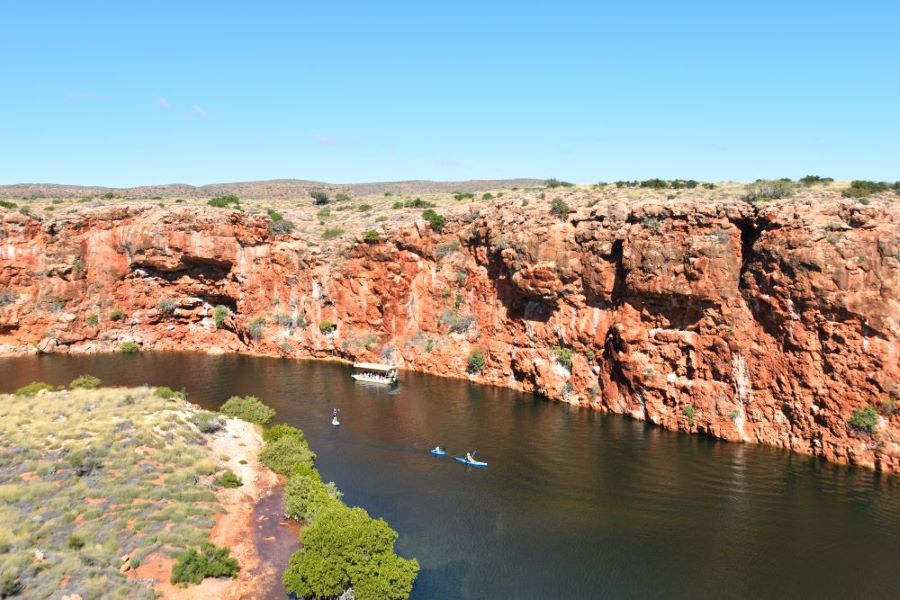 Yardie Creek with kayakers paddling down the creek surrounded by red rock cliffs