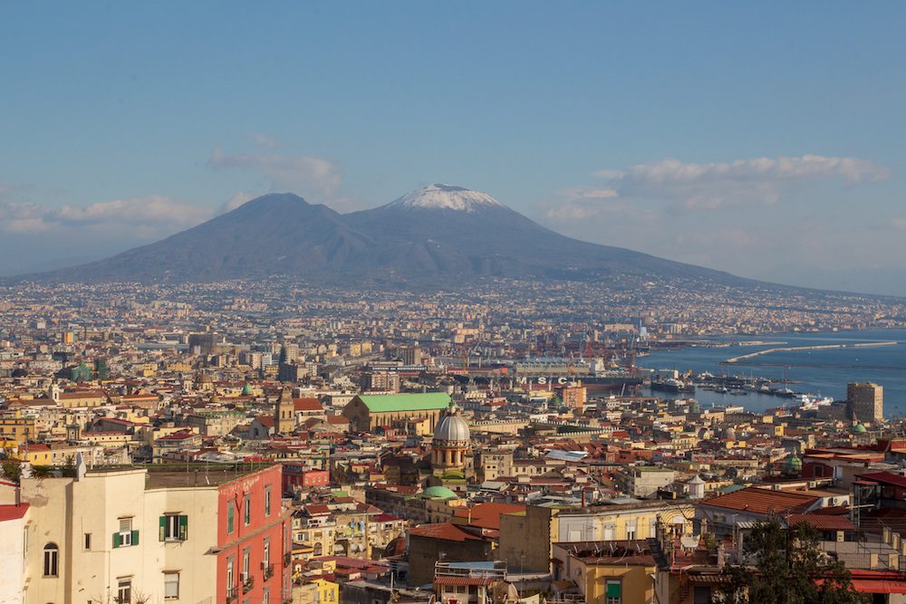 the town of Naples with the snow-capped Mount Vesuvius volcano in the background