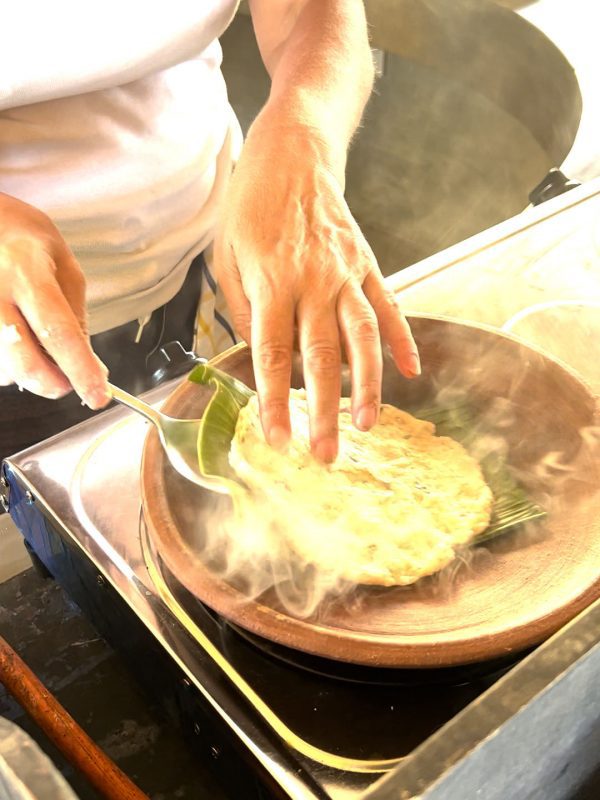 flipping the roti in the pan using fingers to hold the roti