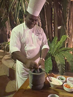 chef in whites mixing ingredients in a grey pestle and mortar
