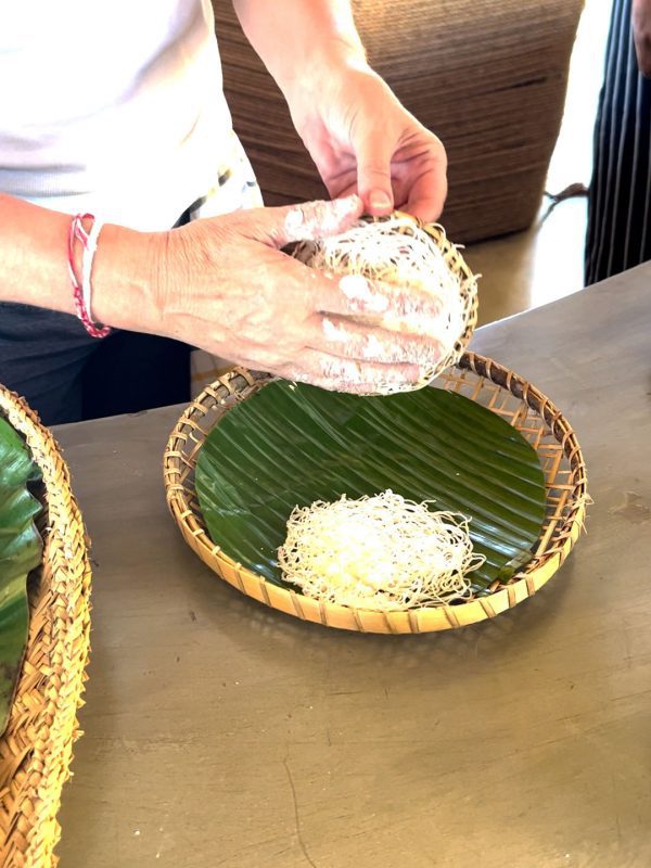removing the string hopper from the bamboo mould and placing on a bamboo plate lined with a banana leaf