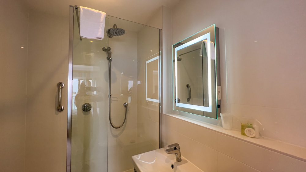 The bathroom of Superior Sea View with digital shower, mirror with lighting. On the shelf are complimentary toiletries