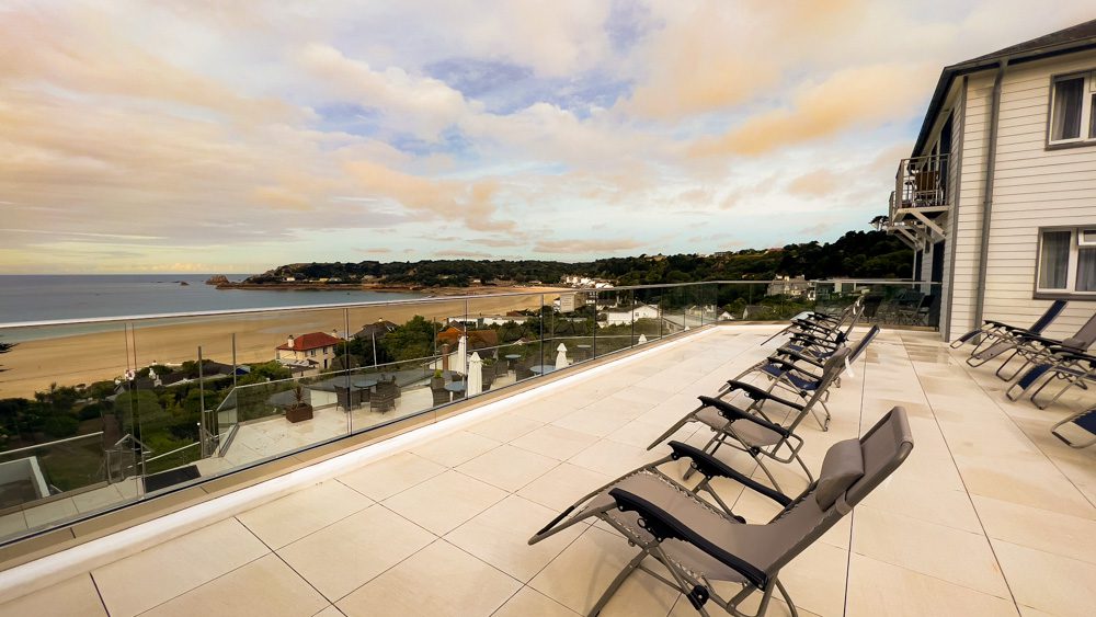 black reclining chairs on the sun terrace at the Biarritz Hotel overlooking St Brelade's Bay