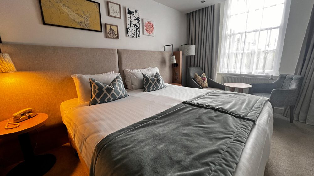 Deluxe Bedroom at Heythrop Park. King size bed with blue cushions with geometric print,