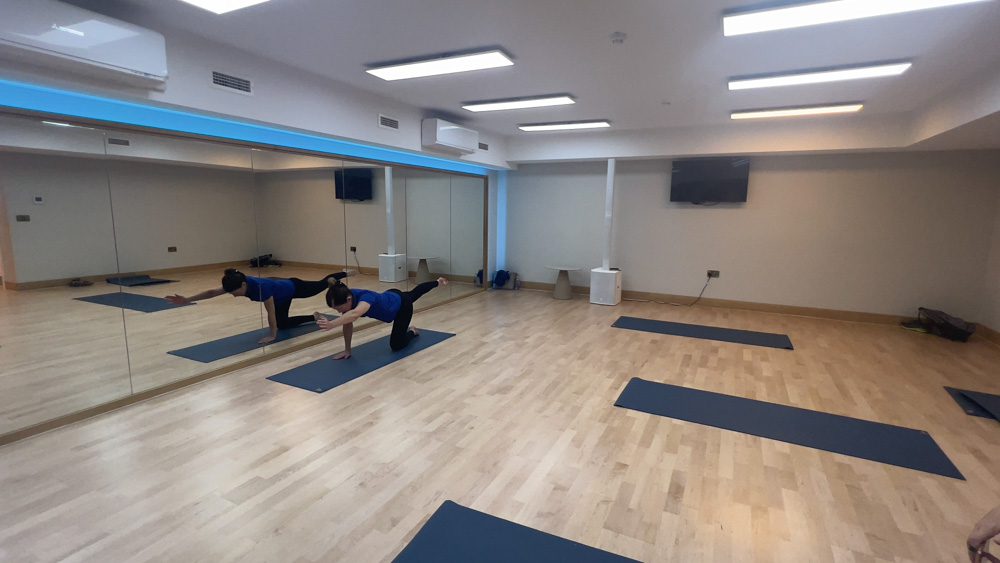 Try Pilates in the airy studio with woman trying a pose on a blue mat