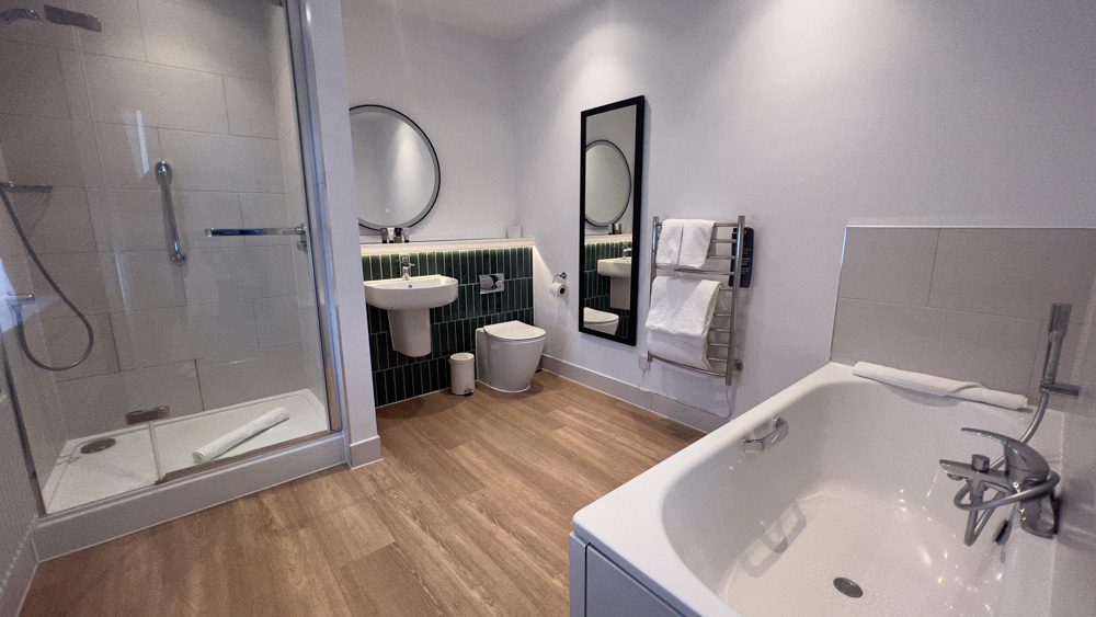 The large bathroom with bath, large shower and large mirrors