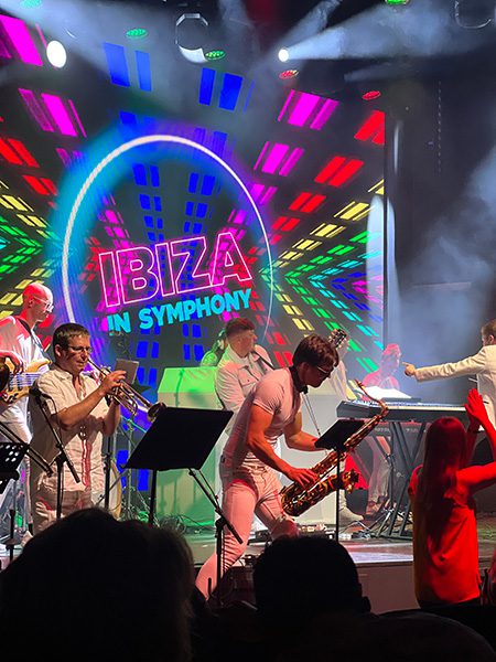 Ibiza in Symphony saxaphone player with Ibiza in Symphony in colour behind