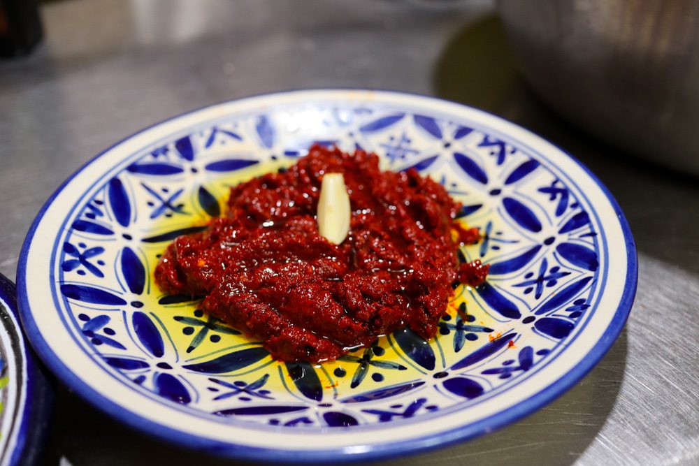 the finished harissa with olive oil and garlic on a blue and white plate