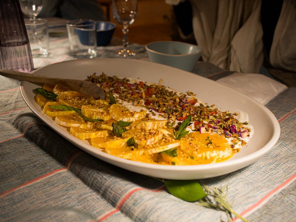 dessert with yoghurt, orange slices rose and pistachios on a white platter