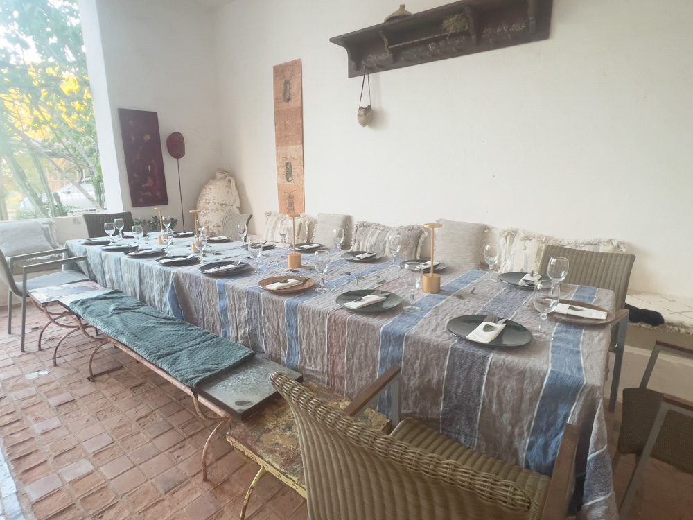 long table with grey and blue striped tablecloth set with plates and glasses