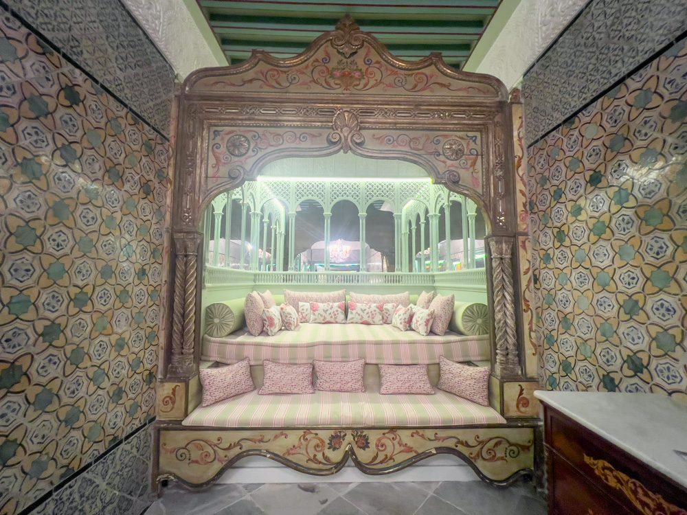 One of the sofa areas upstairs at Dar Jaled tiled in greed and yellow with pink and green cushions and ornate frontage and mirrors