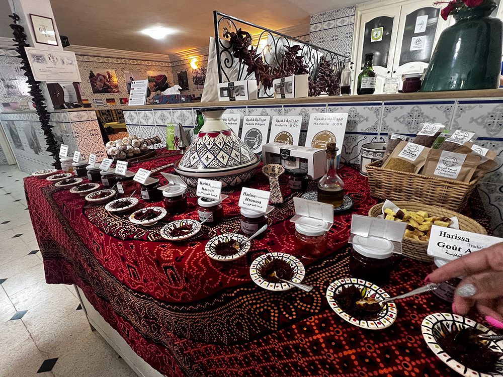 selection of harissas in black and white small dishes with a large tagine behind them