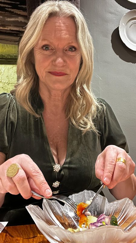 Larch in a green velvet dress enjoying her starter of trout