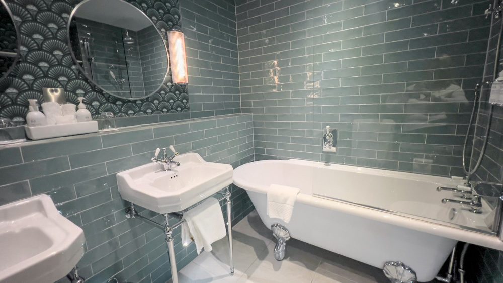 The green tiled bathroom with white stand alone bath