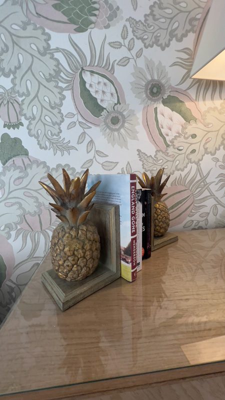 pineapple bookends with a pale green an pink floral wallpaper