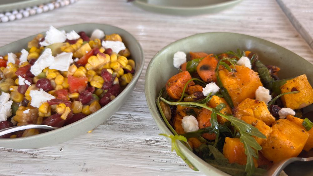corn and feta salad in one green bowl and sweet potato and feta in another