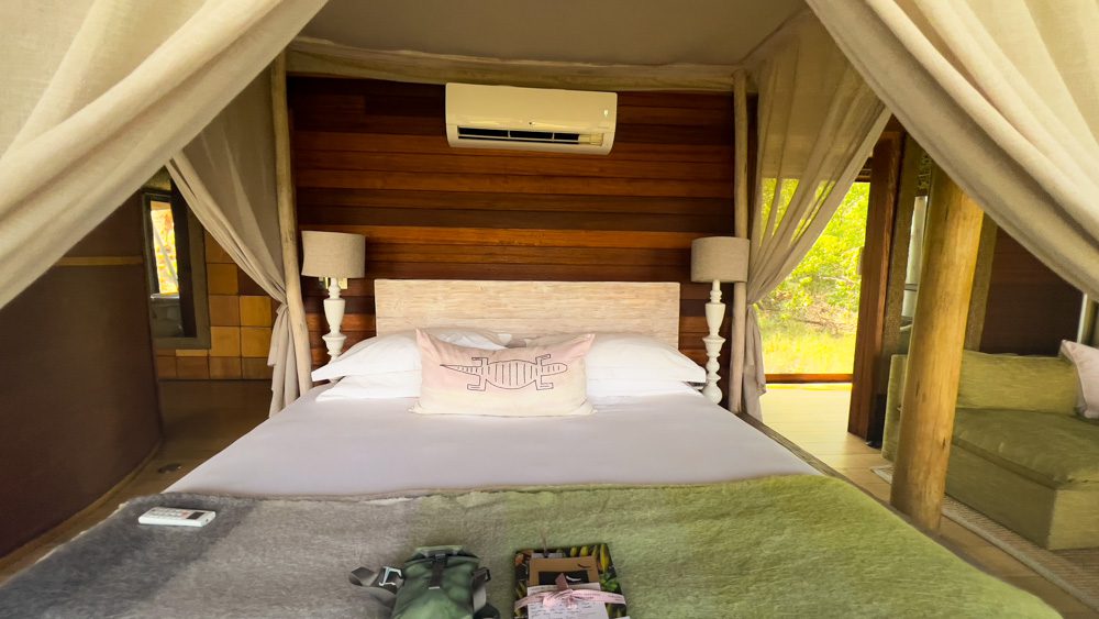 four-postered bed with white linen, drapes and green blanket