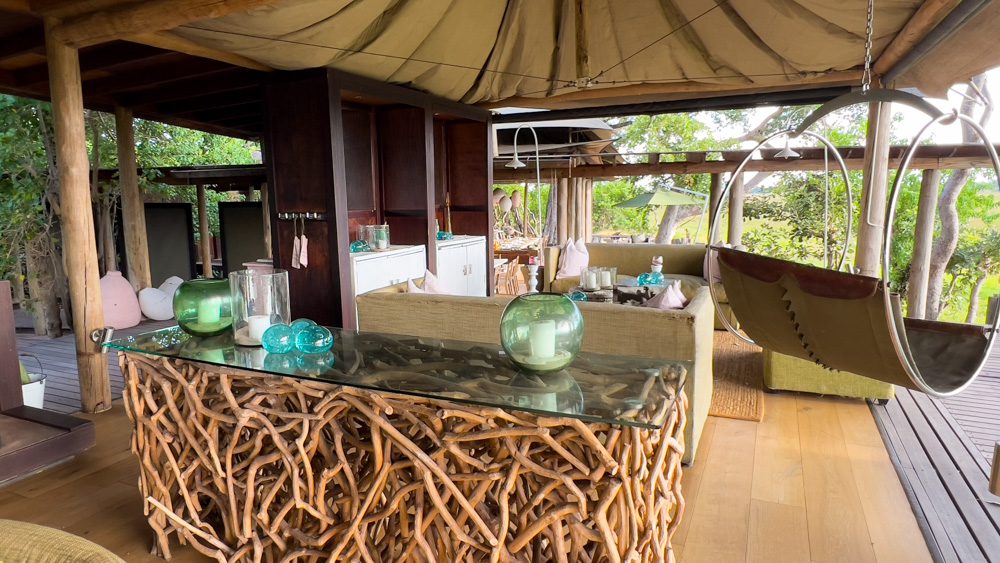 the hanging swing next to the wood and glass table