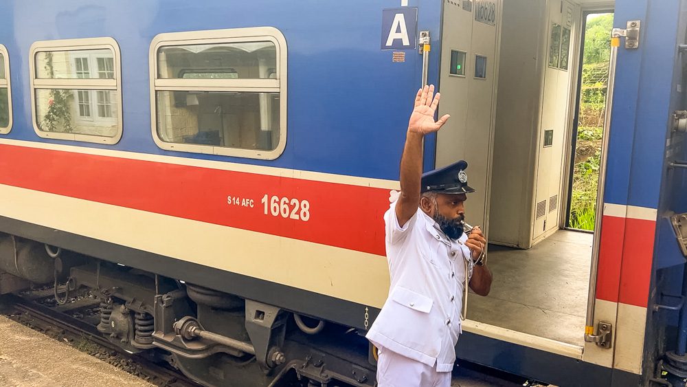 Trains in Sri Lanka with guard blowing his whistle wearing a white uniform