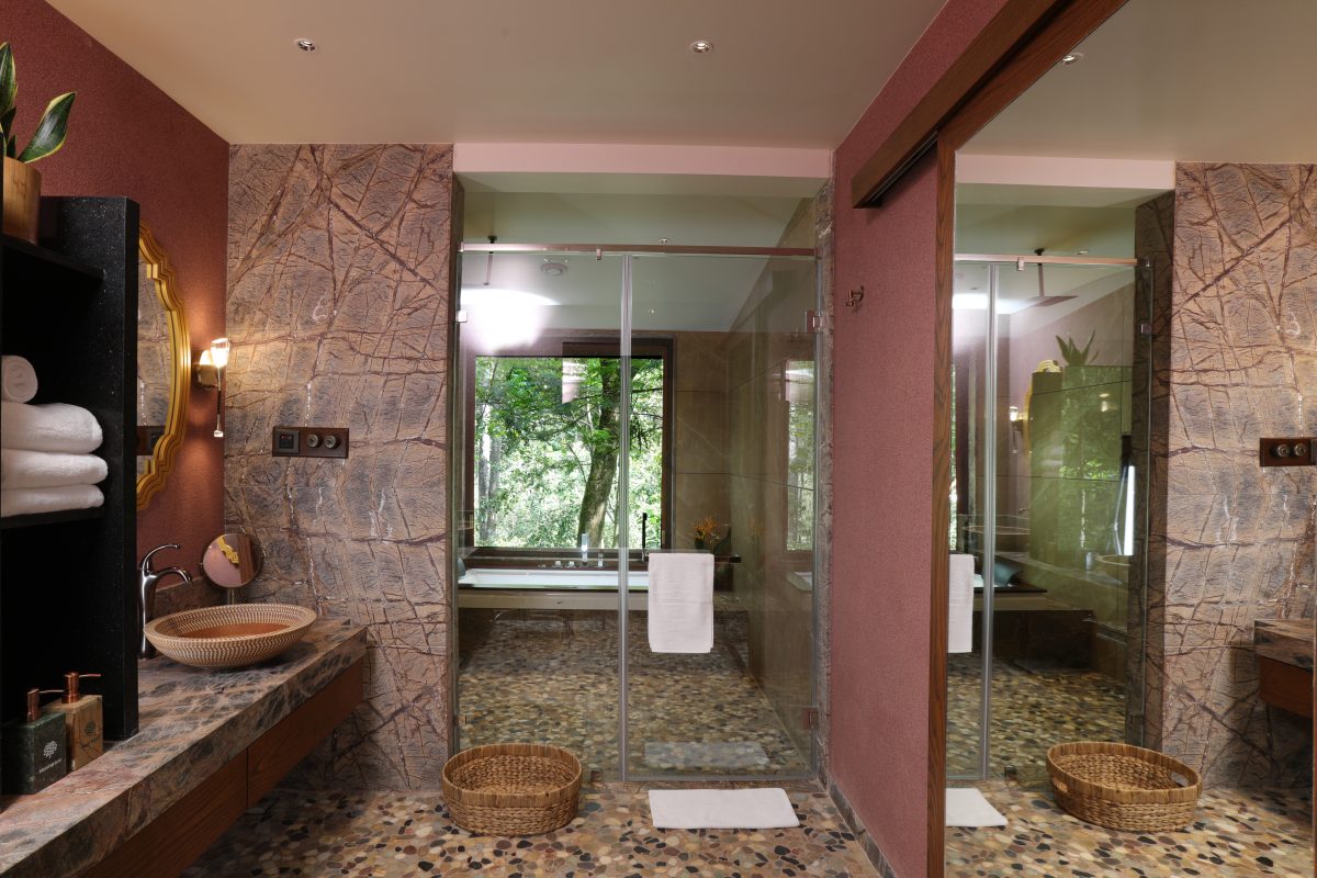 The light and spacious bathrooms with terracotta walls, tiled floors and glass wall separating the bath and shower
