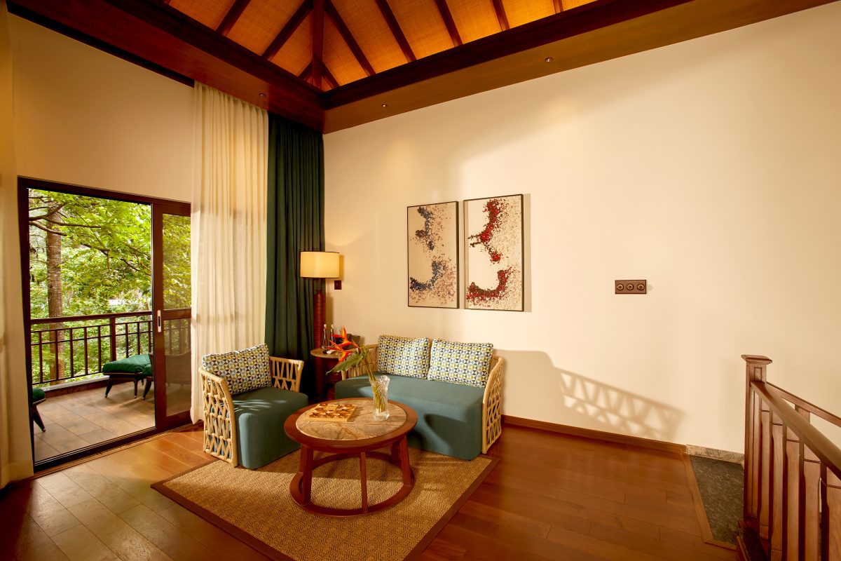 The top floor of the Windchimes Villa with bamboo sofa and chair with turquoise upholstery. Open window leading to the balcony