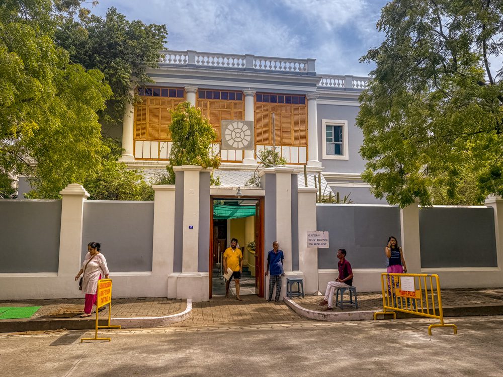The outside of Sri Aurobindo Ashram with grey walls and white pillars