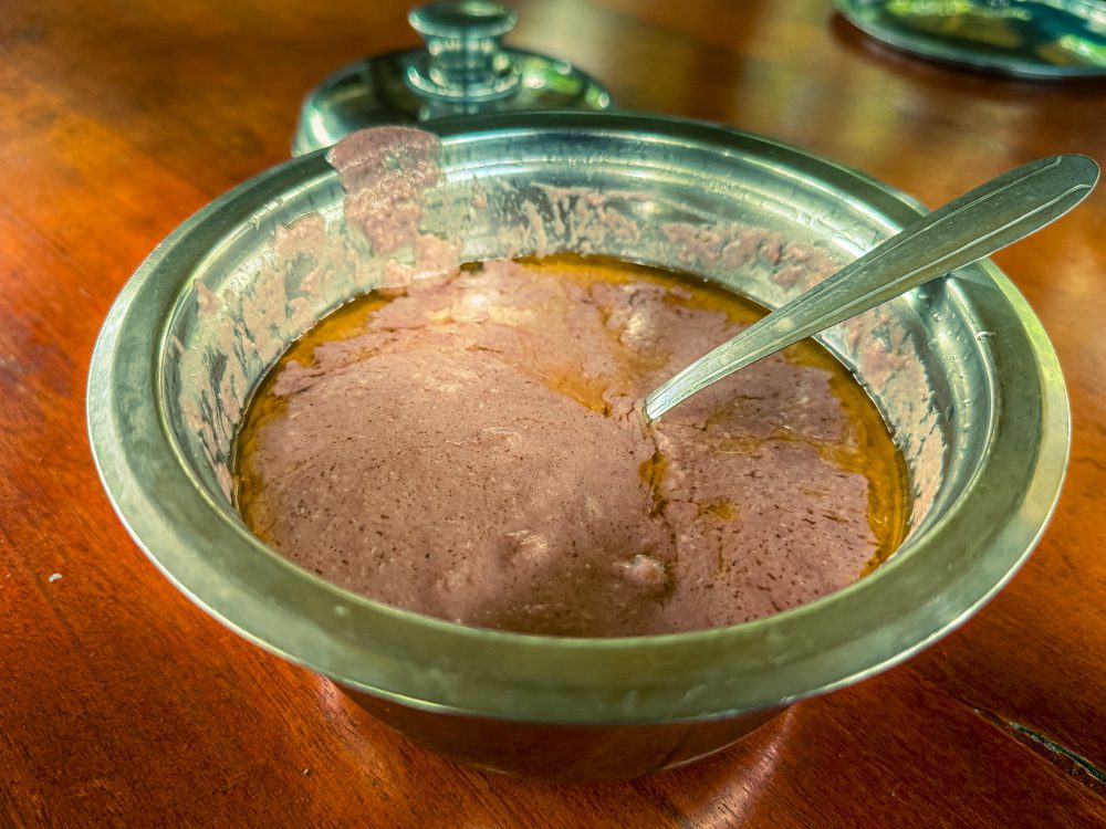 Fresh pink groundnut sauce in a silver metal dish with spoon